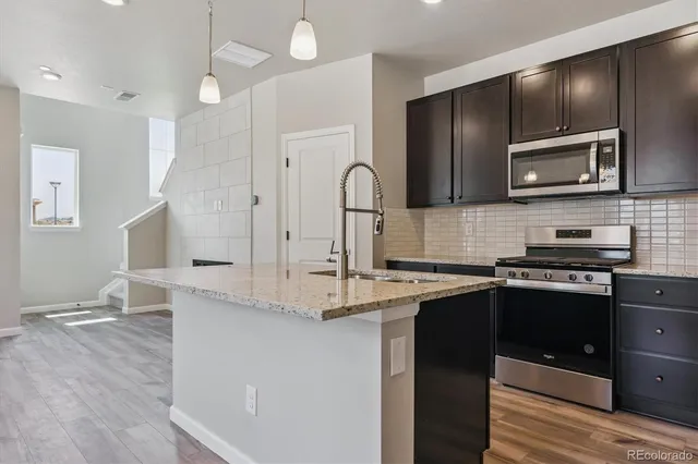 a kitchen with stainless steel appliances granite countertop a stove a sink and a microwave