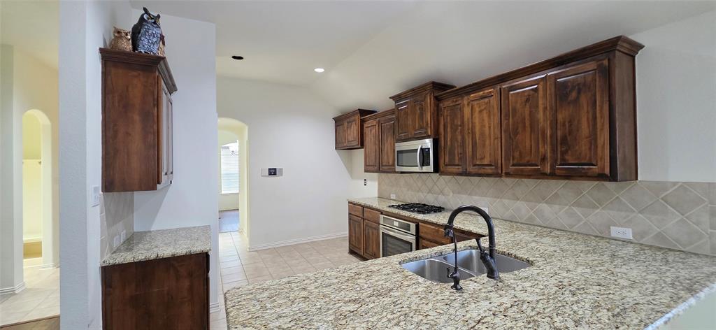 2697 Lake Ridge Drive Little Elm, TX 75068 - Photo 6 of 18 a kitchen with stainless steel appliances granite countertop a sink and a refrigerator
