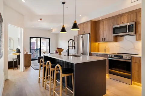 a kitchen with stainless steel appliances granite countertop a stove top oven a sink a dining table and chairs with wooden floor