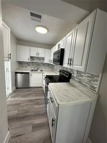 a kitchen with kitchen island granite countertop a sink stove and refrigerator