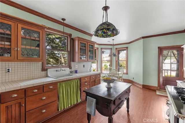 a kitchen with stainless steel appliances granite countertop a sink dishwasher a refrigerator and a dining table with wooden floor