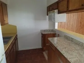 a kitchen with granite countertop cabinets appliances and a counter space