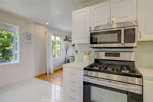 a kitchen with stainless steel appliances granite countertop white cabinets a stove top oven a sink and dishwasher