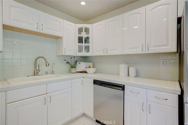 a kitchen with white cabinets and sink