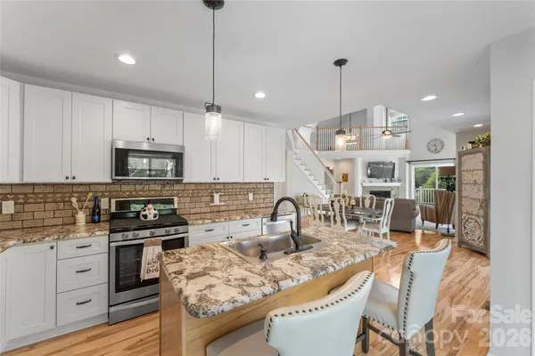 a kitchen with stainless steel appliances kitchen island granite countertop a stove a sink a oven a dining table and chairs