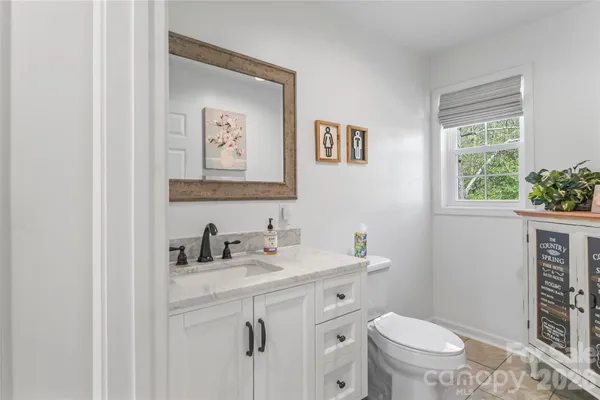 a bathroom with a toilet a sink a mirror a window and vanity