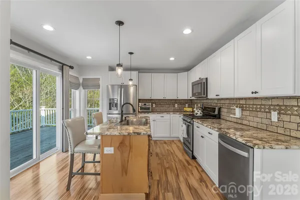 a large kitchen with kitchen island a large window cabinets and stainless steel appliances
