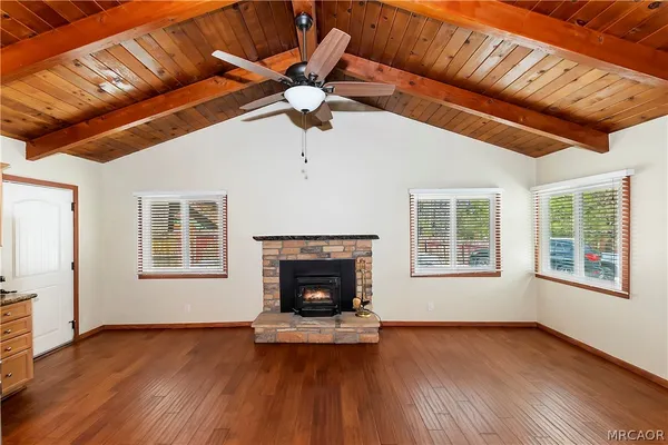 a view of an empty room with wooden floor fireplace and a window