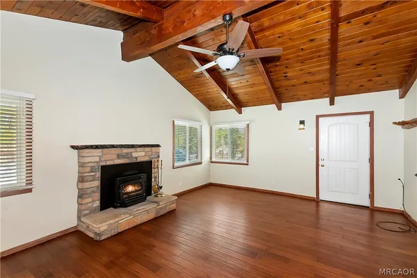 a view of an empty room with wooden floor fireplace and a window