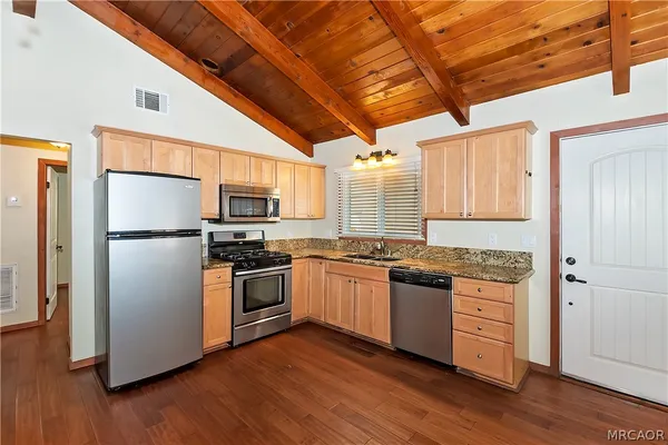 a kitchen with granite countertop stainless steel appliances and wooden floor