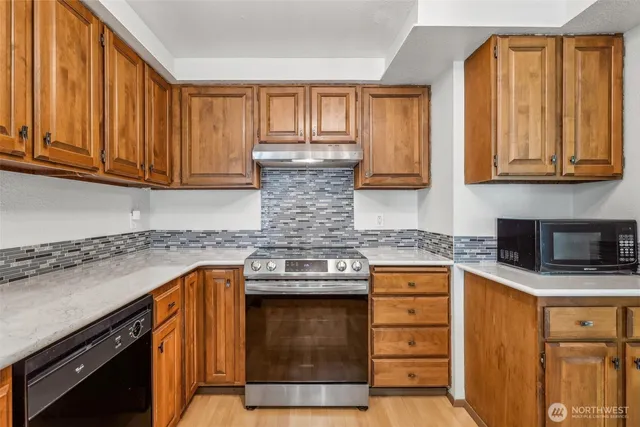 a kitchen with granite countertop cabinets stainless steel appliances a sink and wooden floor