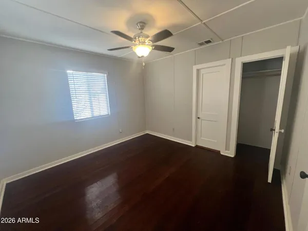 an empty room with wooden floor fan and windows