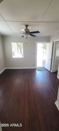an empty room with wooden floor chandelier and windows