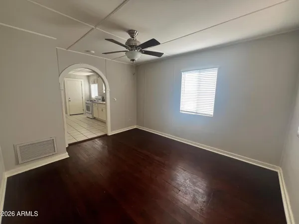 an empty room with wooden floor fan and windows