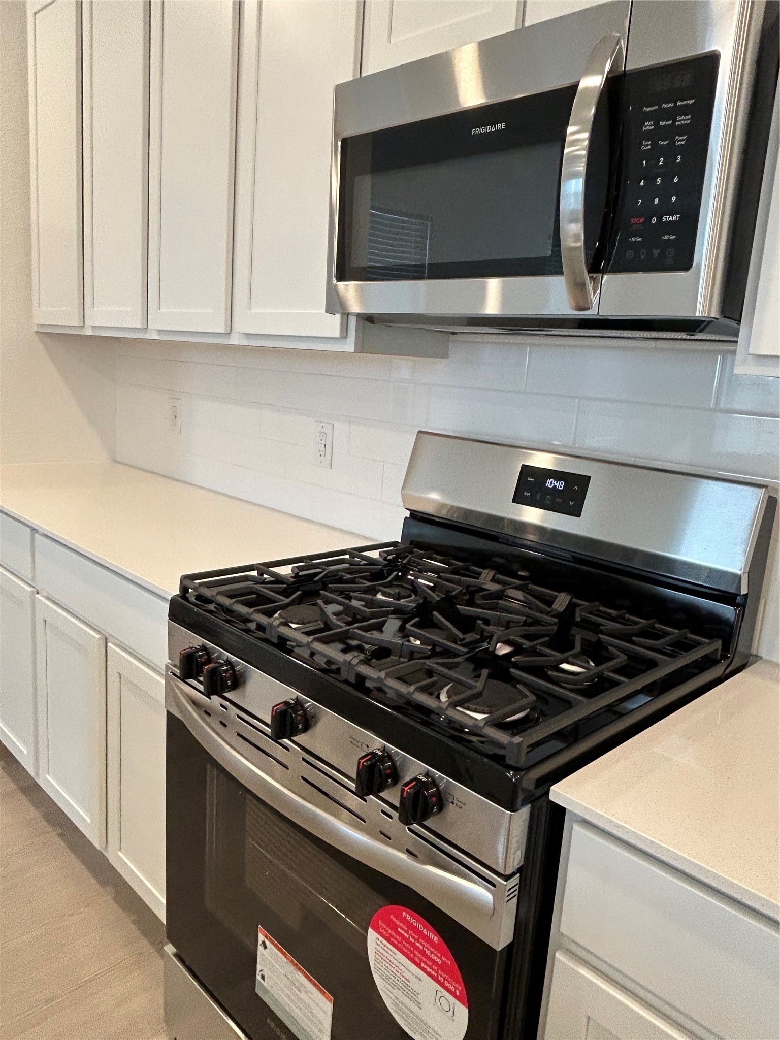 26419 Virginia Wild Rye Lane Katy, TX 77493 - Photo 14 of 31 Modern kitchen featuring stainless steel appliances, including a gas stove and microwave, with sleek white cabinetry and countertops. Ideal for culinary enthusiasts.