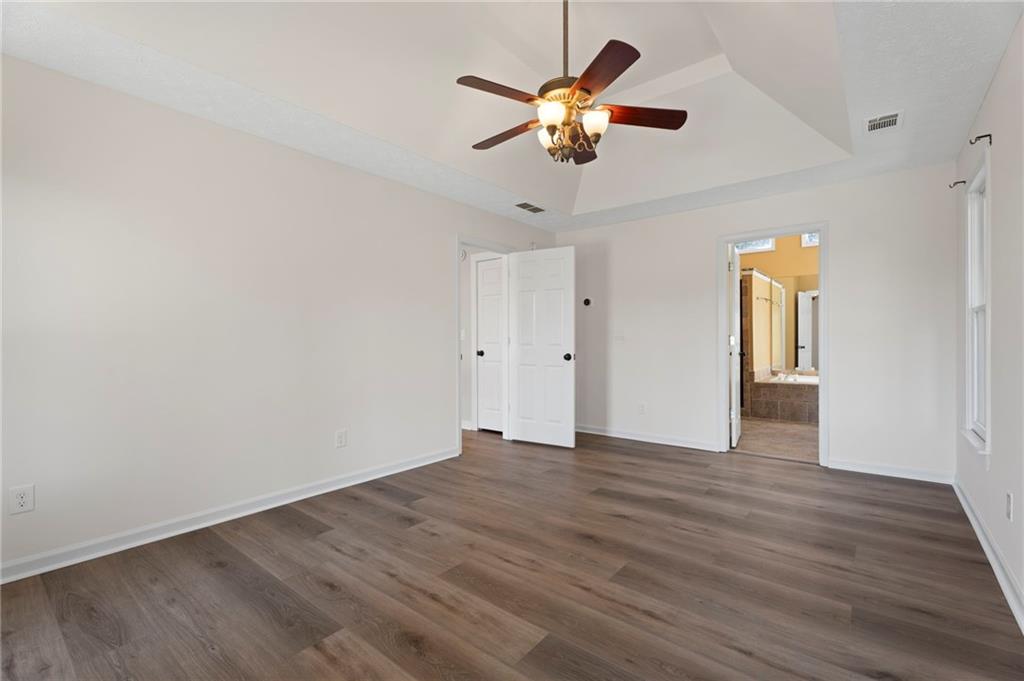 1381 Gateswalk Path Lawrenceville, GA 30045 - Photo 34 of 45 an empty room with wooden floor chandelier fan and windows