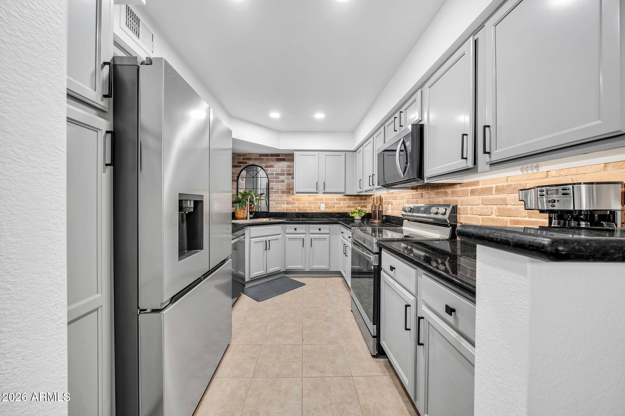 8787 East Mountain View Road, Unit 2038 Scottsdale, AZ 85258 - Photo 17 of 37 a kitchen with stainless steel appliances granite countertop a refrigerator a sink dishwasher a stove and white countertops with wooden floor