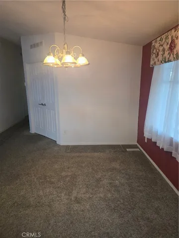 an empty room with a chandelier fan and windows