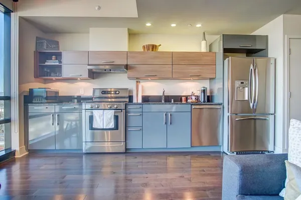 a kitchen with stainless steel appliances granite countertop a refrigerator a sink a stove and oven