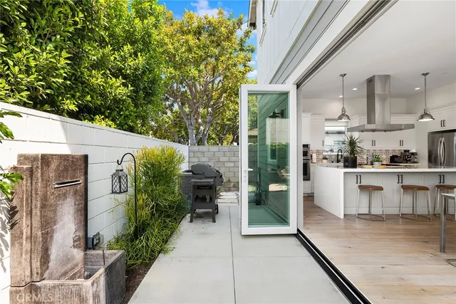 a view of a patio with table and chairs potted plants with floor to ceiling window and wooden fence