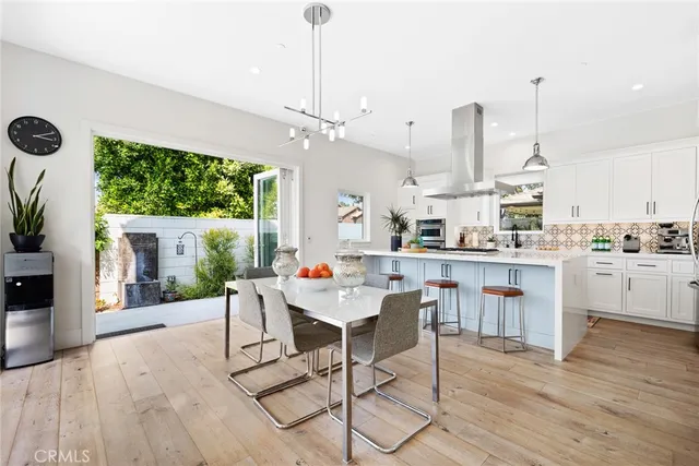 a kitchen with stainless steel appliances kitchen island granite countertop a refrigerator a stove a sink dishwasher and white cabinets with wooden floor