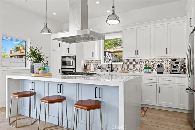 a kitchen with stainless steel appliances a white table chairs and a wooden floor