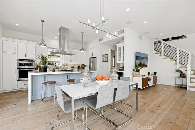 a kitchen with stainless steel appliances kitchen island granite countertop a table chairs and a refrigerator