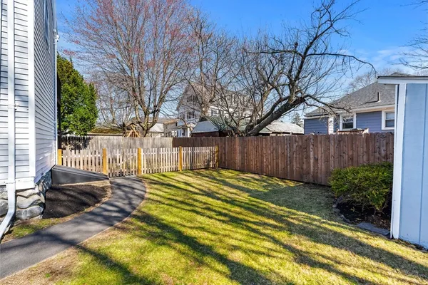 a view of a backyard with wooden fence and a large tree