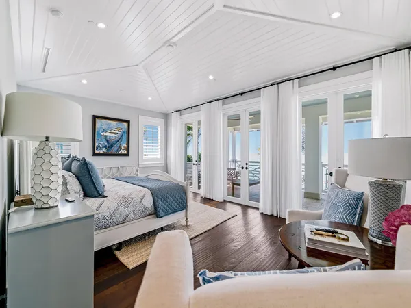 a bedroom with a bed couches and a flat tv screen