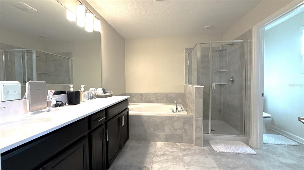 1055 Blackwolf Run Road Davenport, FL 33896 - Photo 8 of 23 a bathroom with a granite countertop sink a toilet and shower