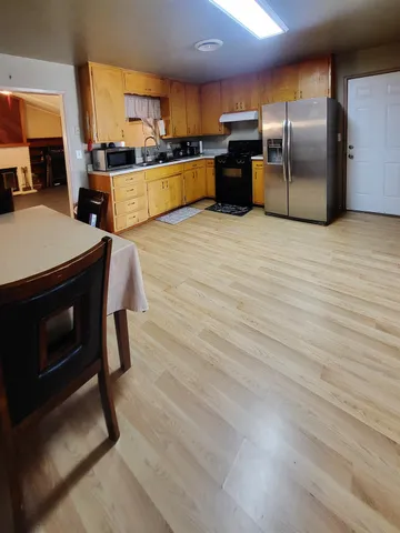 a kitchen with stainless steel appliances wooden floor and a refrigerator