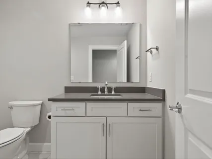 a bathroom with a granite countertop sink and a toilet