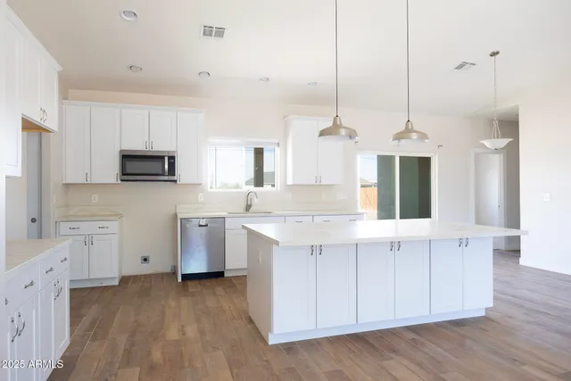 a kitchen with stainless steel appliances a sink stove and wooden floor