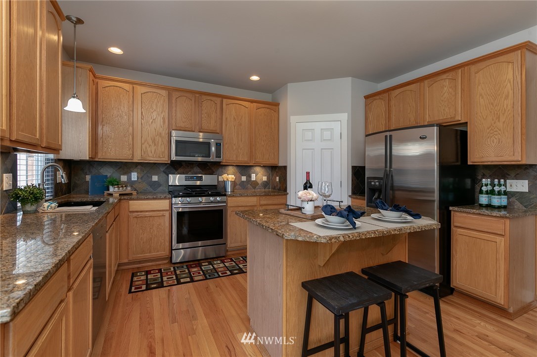 204 203rd Street Southeast Bothell, WA 98012 - Photo 5 of 25 a kitchen with a stove a sink a microwave a refrigerator and cabinets