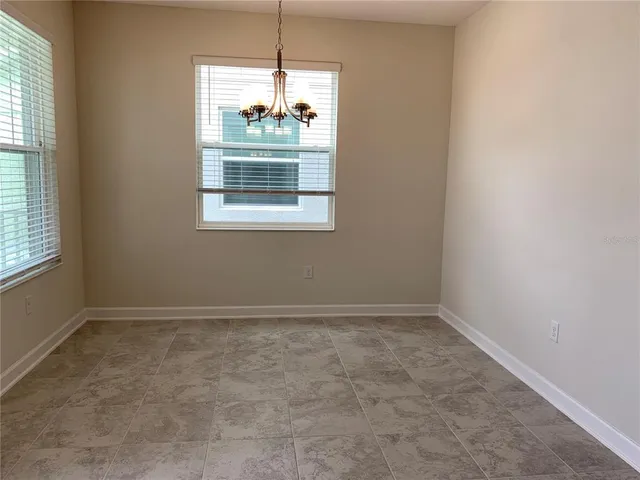 an empty room with chandelier fan and windows