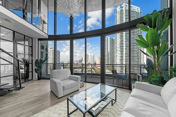 a living room with furniture a floor to ceiling window and wooden floor