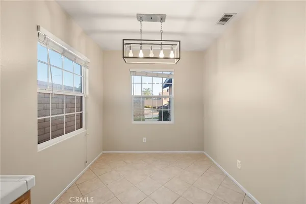 an empty room with chandelier fan and windows