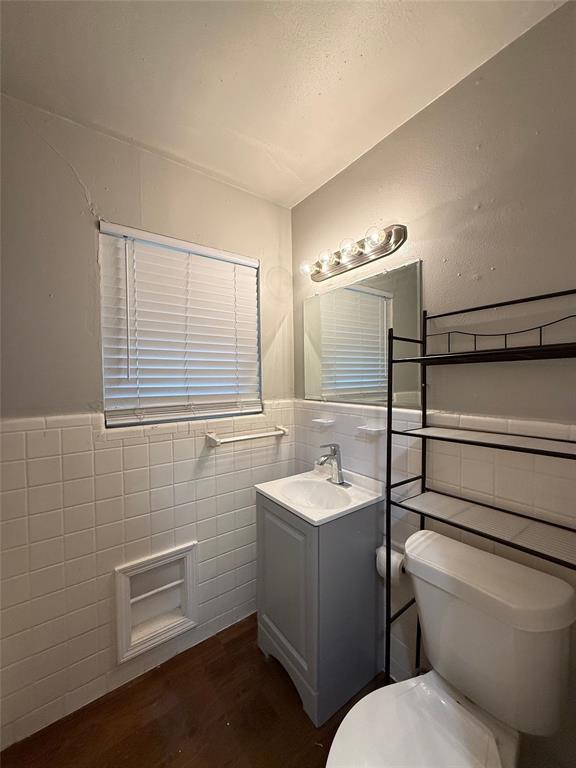 4815 Live Oak Street, Unit 10 Dallas, TX 75204 - Photo 7 of 13 Bathroom featuring tile walls, a wainscoted wall, vanity, and dark wood finished floors