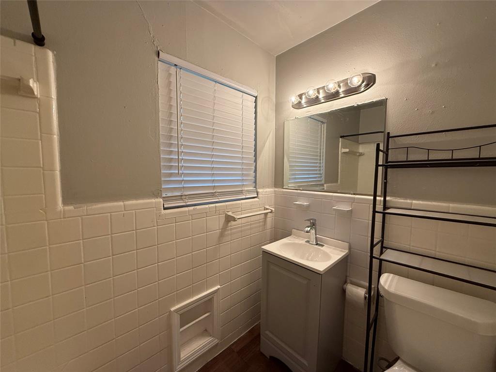 4815 Live Oak Street, Unit 10 Dallas, TX 75204 - Photo 8 of 13 Bathroom featuring vanity, tile walls, and a wainscoted wall