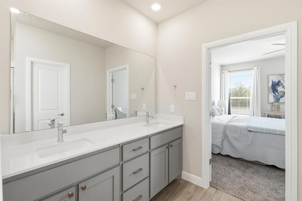317 Hogan Drive Denton, TX 76210 - Photo 19 of 30 a en suite bathroom with a double vanity sink a mirror and next to a window