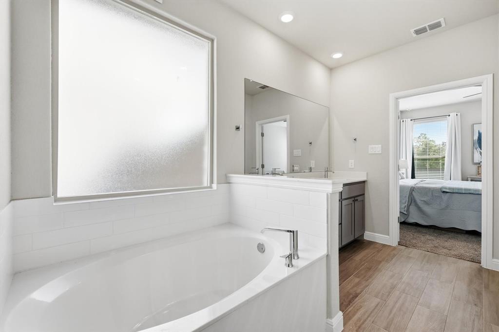317 Hogan Drive Denton, TX 76210 - Photo 20 of 30 a bathroom with a bathtub a mirror a sink and vanity