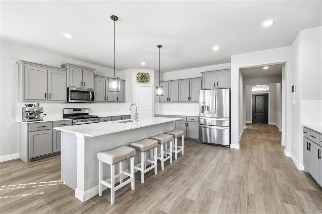 317 Hogan Drive Denton, TX 76210 - Photo 2 of 30 a kitchen with stainless steel appliances granite countertop a refrigerator a stove top oven a sink dishwasher and white cabinets with wooden floor