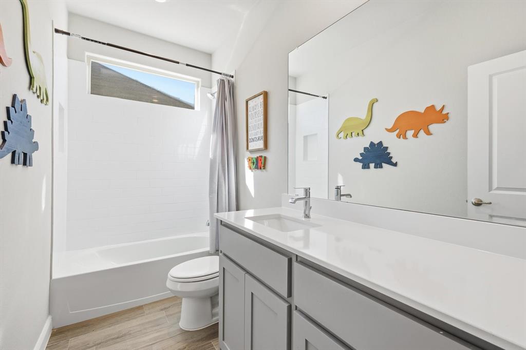 317 Hogan Drive Denton, TX 76210 - Photo 25 of 30 a bathroom with a granite countertop sink a toilet and a bathtub