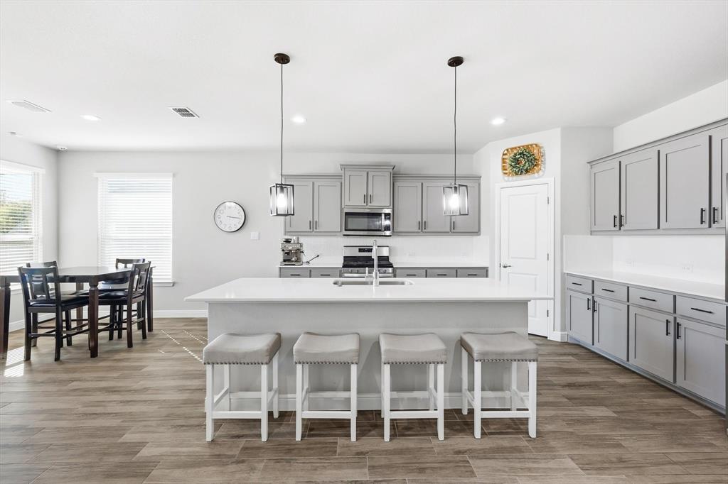 317 Hogan Drive Denton, TX 76210 - Photo 7 of 30 a kitchen with stainless steel appliances kitchen island granite countertop a dining table chairs and white cabinets