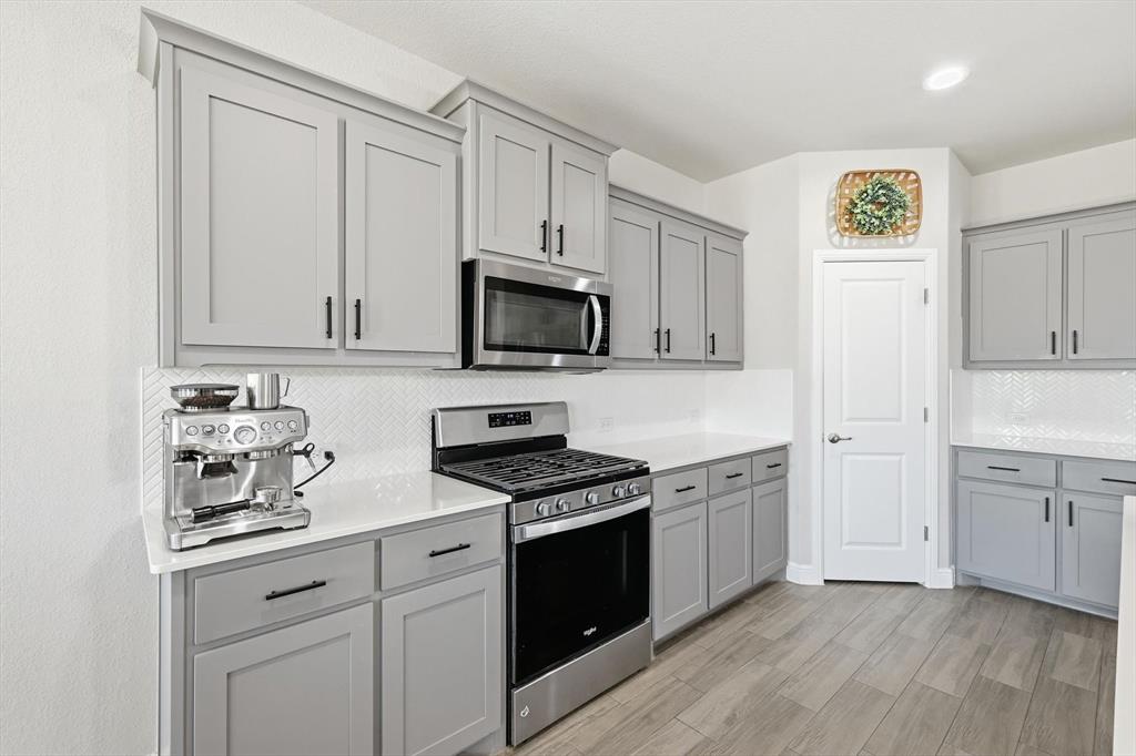 317 Hogan Drive Denton, TX 76210 - Photo 9 of 30 a kitchen with white cabinets and black appliances