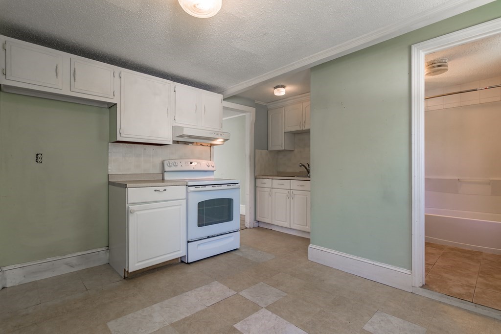 139 Baldwin Street Lowell, MA 01851 - Photo 15 of 39 a kitchen with white cabinets and white appliances