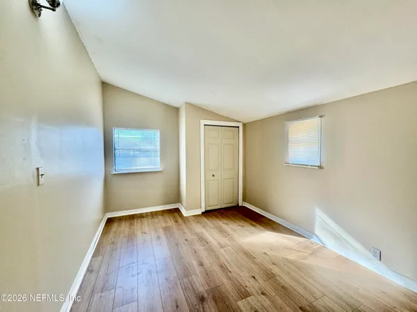 a view of an empty room with wooden floor and a window