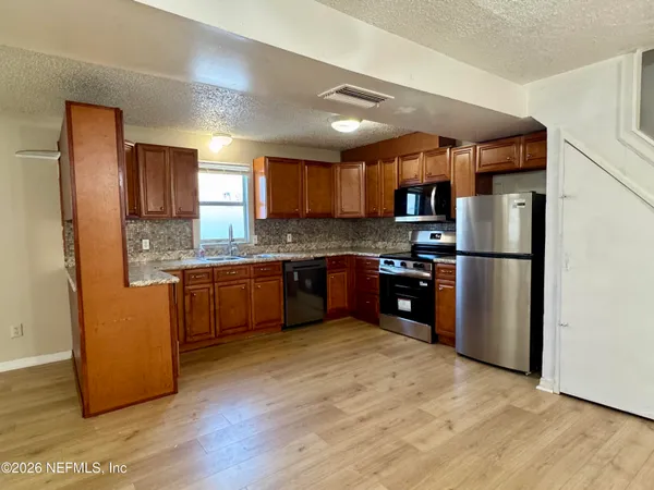 a kitchen with granite countertop stainless steel appliances a refrigerator a sink a stove a microwave and cabinets