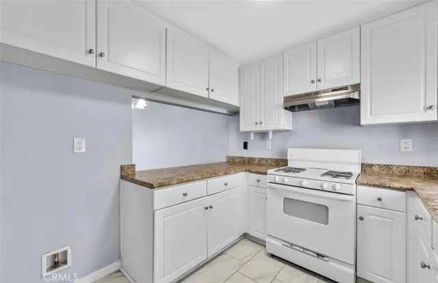 a kitchen with granite countertop white cabinets and white appliances