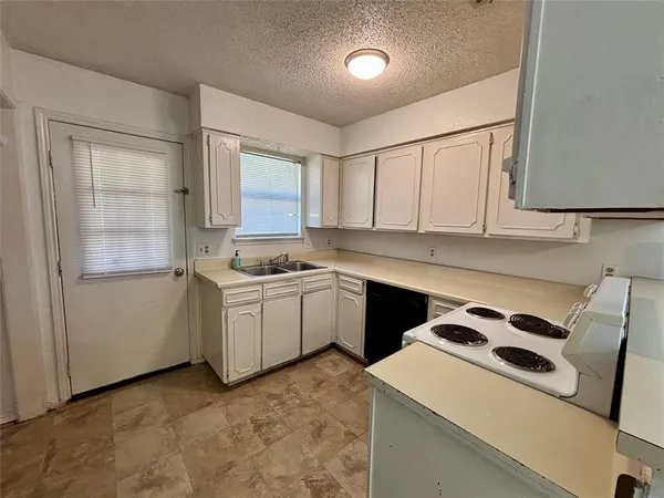 a view of a refrigerator in kitchen and an empty room in wooden floor
